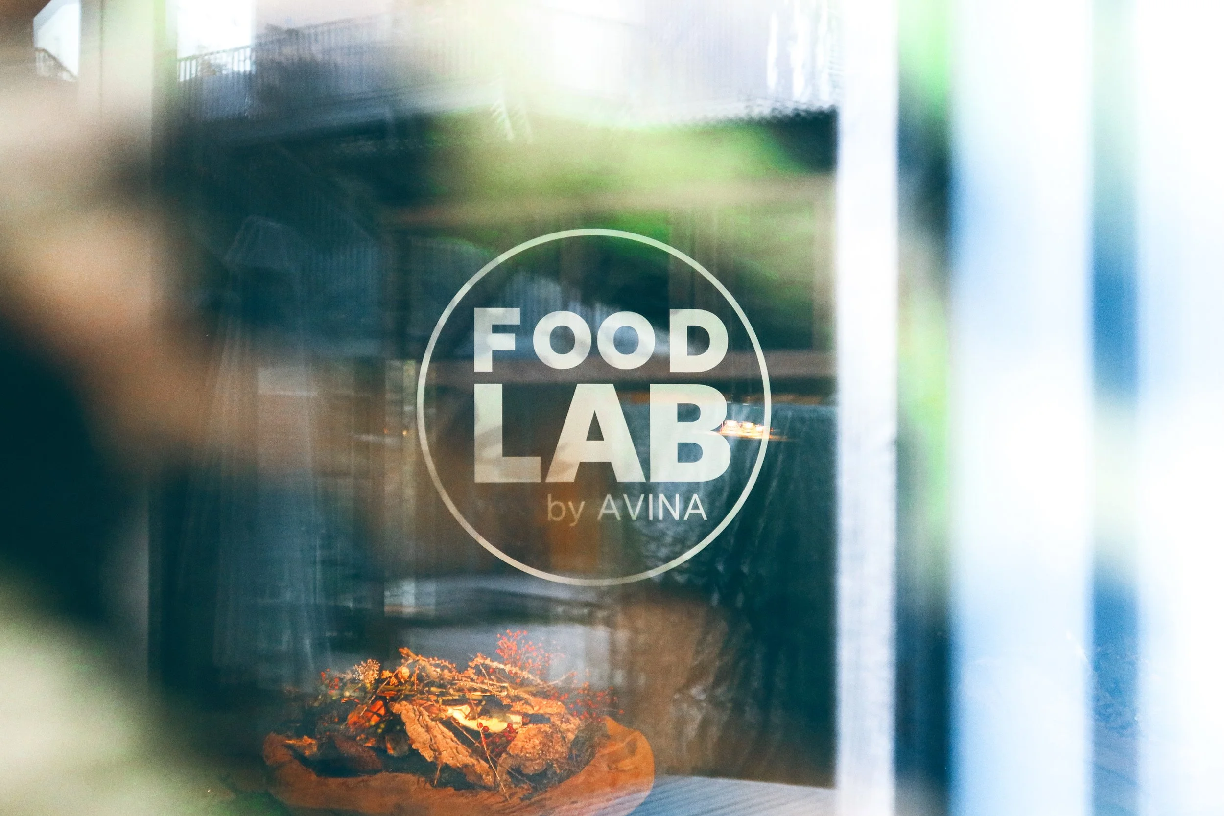 A container or cup featuring the logo 'Food Lab by Avina' on its surface, with an image of a fire or embers at the bottom of the container.
