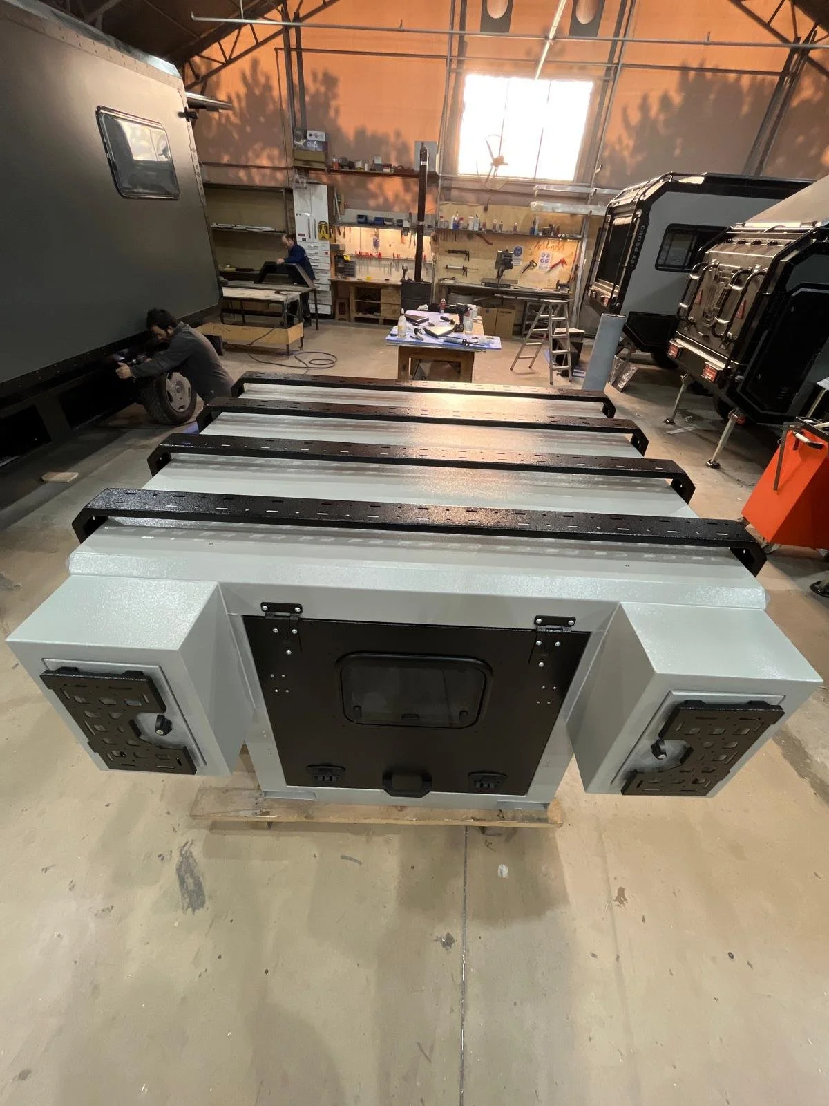 Demountable DEBOXS universal pickup storage system. Featuring integrated roof bars for roof cargo such as ladders, or rooftop tents, this rugged adventure and work canopy replacement offers a non-invasive mounting system that protects vehicle lease r