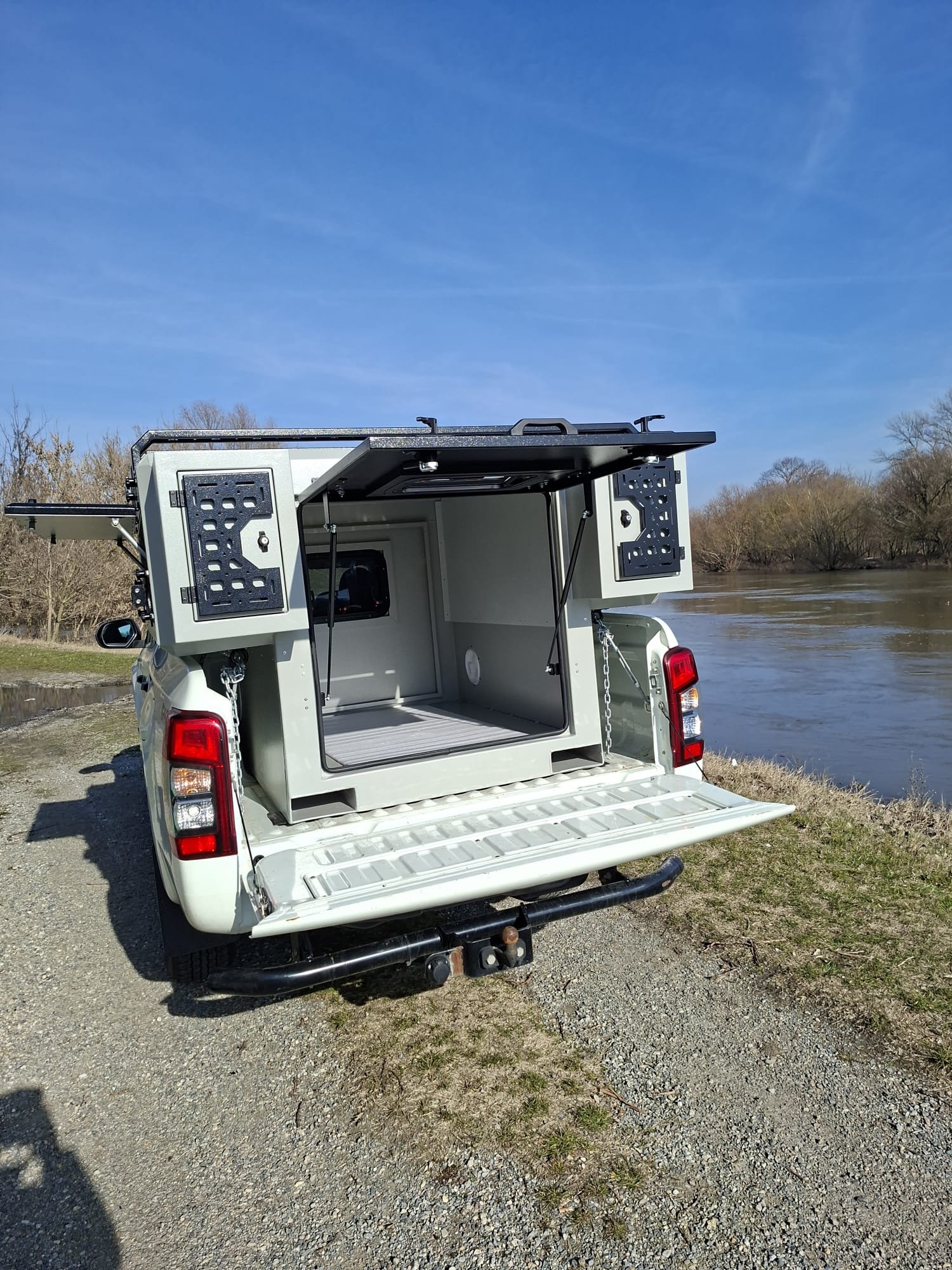 Demountable DEBOXS universal pickup storage system. Featuring integrated roof bars for roof cargo such as ladders, or rooftop tents, this rugged adventure and work canopy replacement offers a non-invasive mounting system that protects vehicle lease r