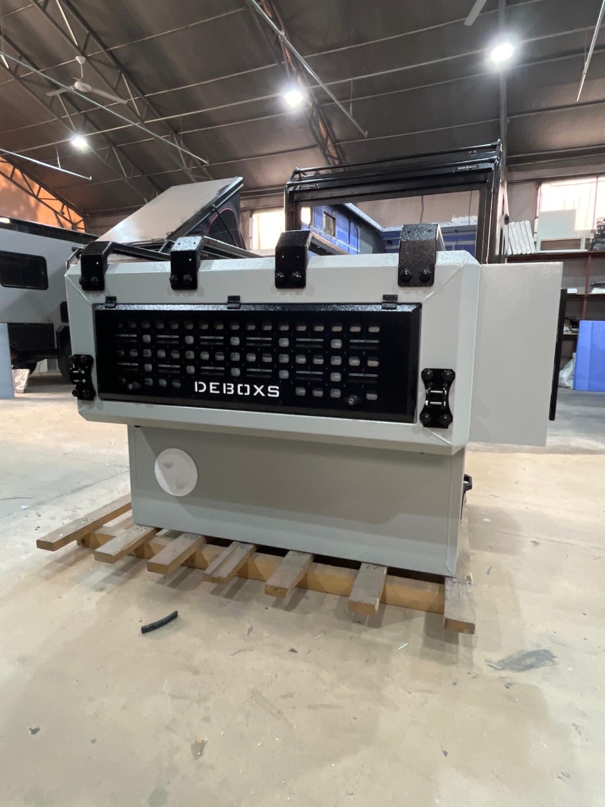 Demountable DEBOXS universal pickup storage system. Featuring integrated roof bars for roof cargo such as ladders, or rooftop tents, this rugged adventure and work canopy replacement offers a non-invasive mounting system that protects vehicle lease r