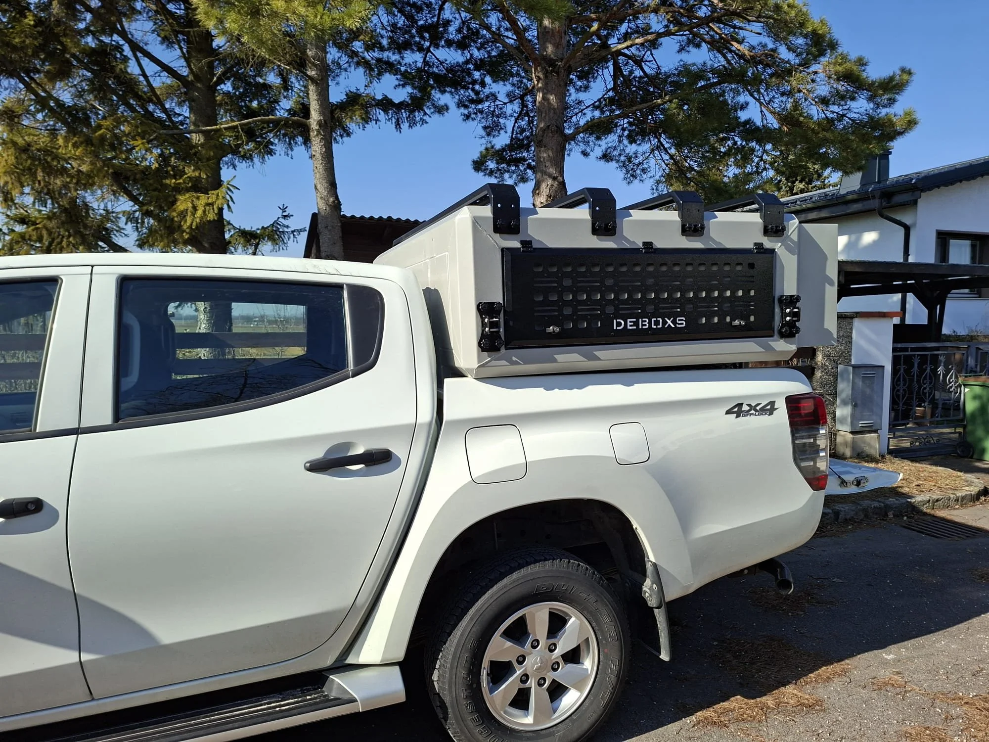 Demountable DEBOXS universal pickup storage system. Featuring integrated roof bars for roof cargo such as ladders, or rooftop tents, this rugged adventure and work canopy replacement offers a non-invasive mounting system that protects vehicle lease r