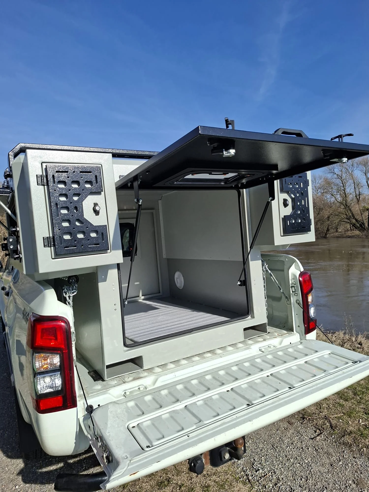 Demountable DEBOXS universal pickup storage system. Featuring integrated roof bars for roof cargo such as ladders, or rooftop tents, this rugged adventure and work canopy replacement offers a non-invasive mounting system that protects vehicle lease r