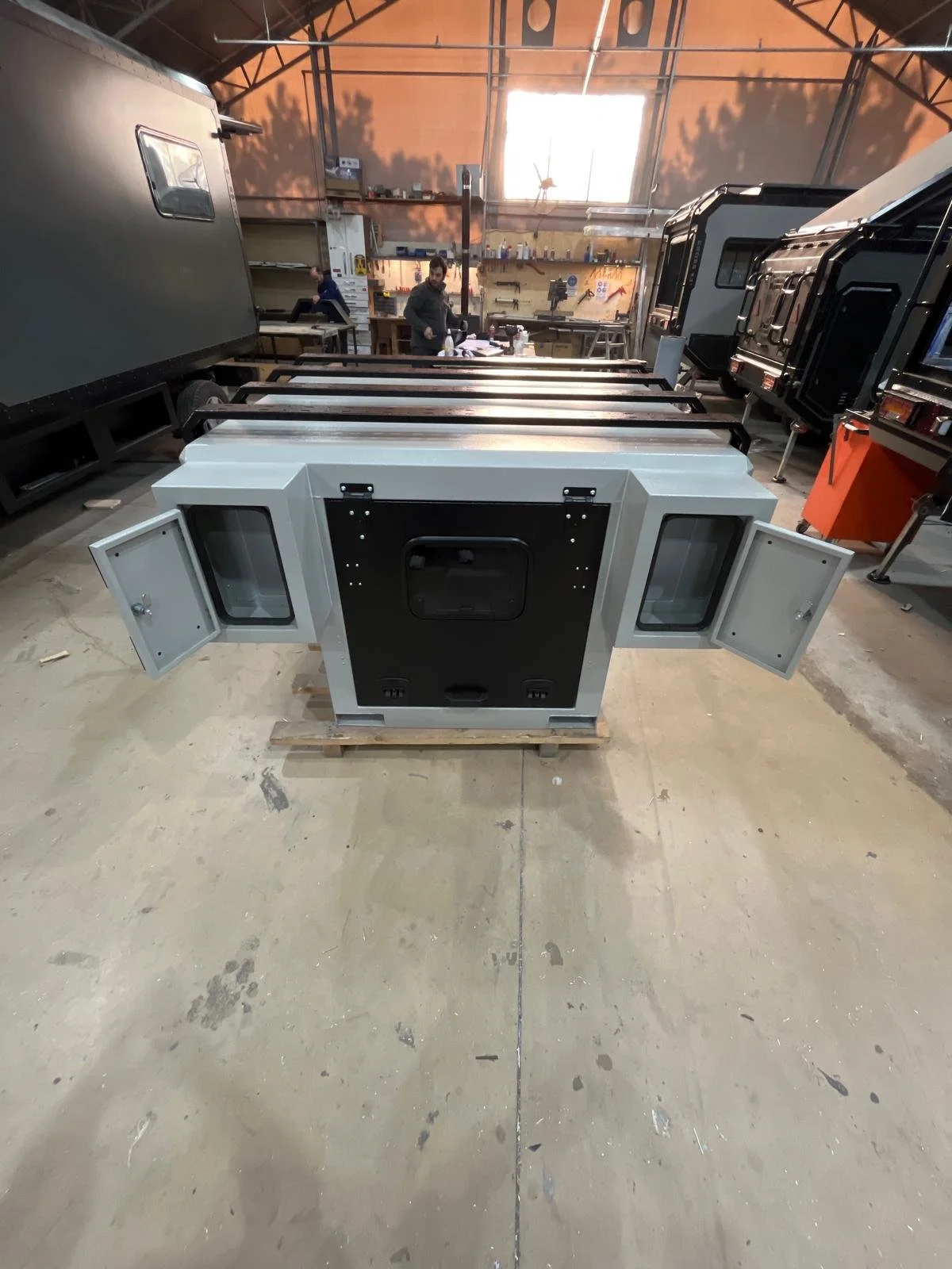 Demountable DEBOXS universal pickup storage system. Featuring integrated roof bars for roof cargo such as ladders, or rooftop tents, this rugged adventure and work canopy replacement offers a non-invasive mounting system that protects vehicle lease r