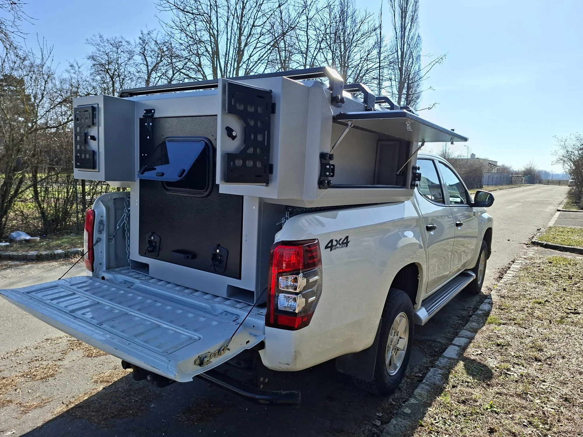 Demountable DEBOXS universal pickup storage system. Featuring integrated roof bars for roof cargo such as ladders, or rooftop tents, this rugged adventure and work canopy replacement offers a non-invasive mounting system that protects vehicle lease r