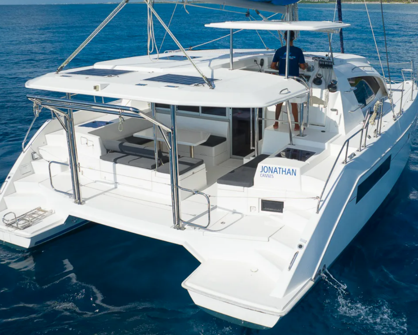 Yate blanco en el agua con una persona en la cabina y una señal que dice 'Jonathan Cannes'