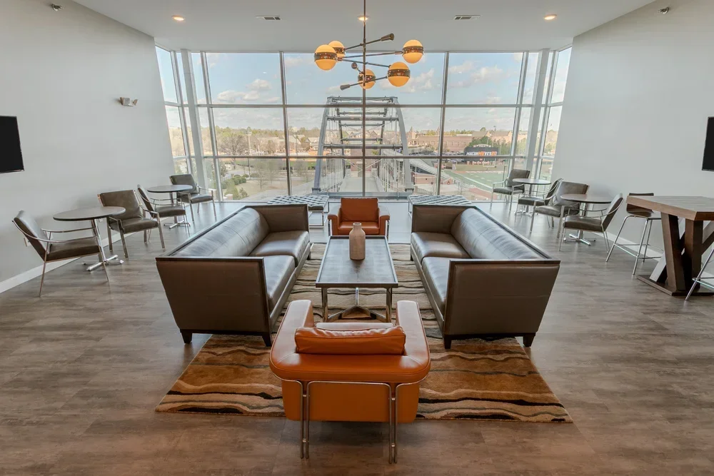 The Skyroom at Lofts at Mercer Landing overlooking Macon, GA featuring leather couches, floor-to-ceiling windows, and community space to lounge in the apartment building.