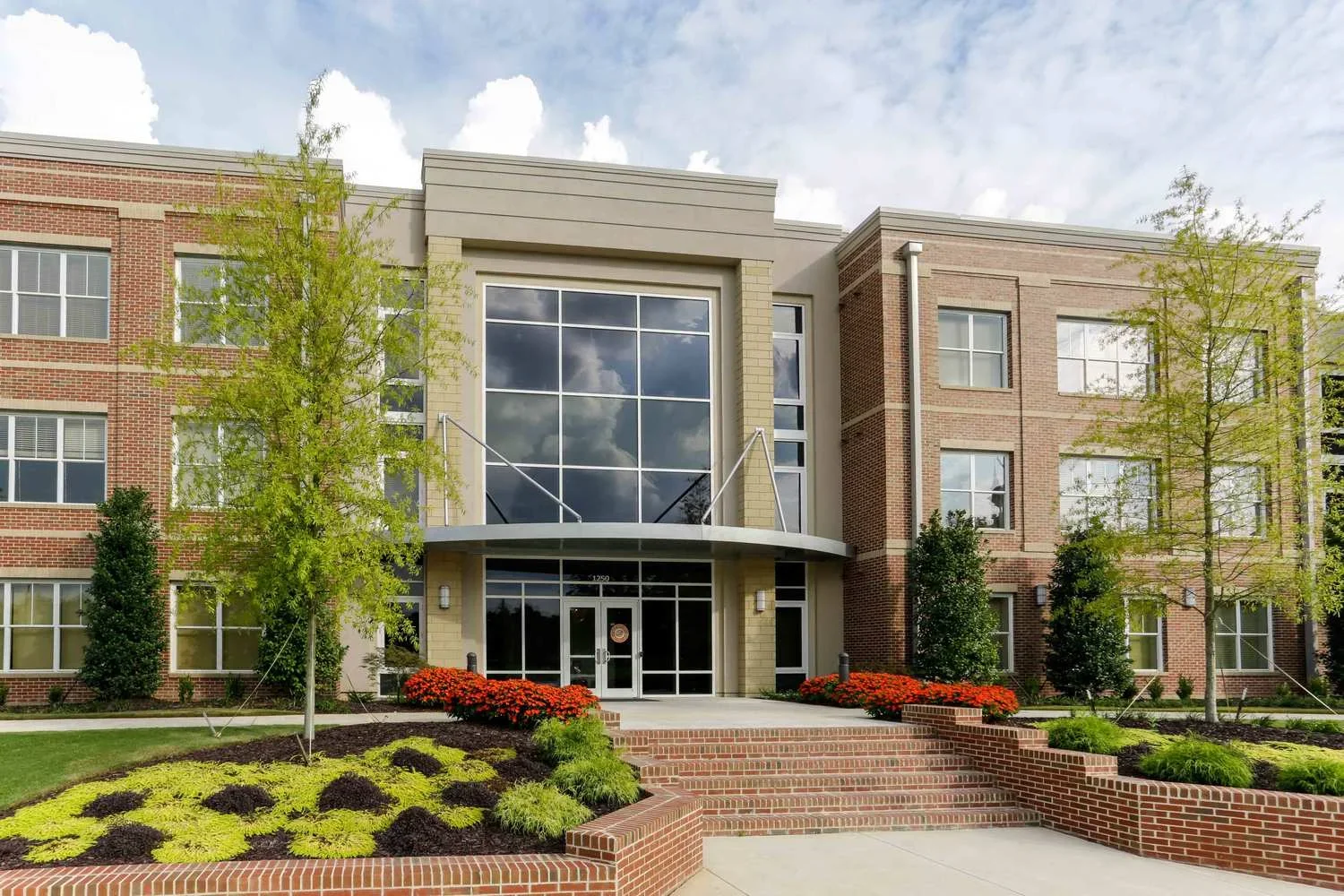 Main apartment building of Lofts at Tattnall in Macon, GA near Mercer University with large windows, three floors of apartments against a blue sky.