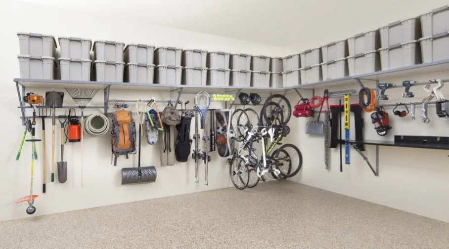 Garage wall with organized outdoor tools, sports equipment, and a bicycle, with storage bins above.