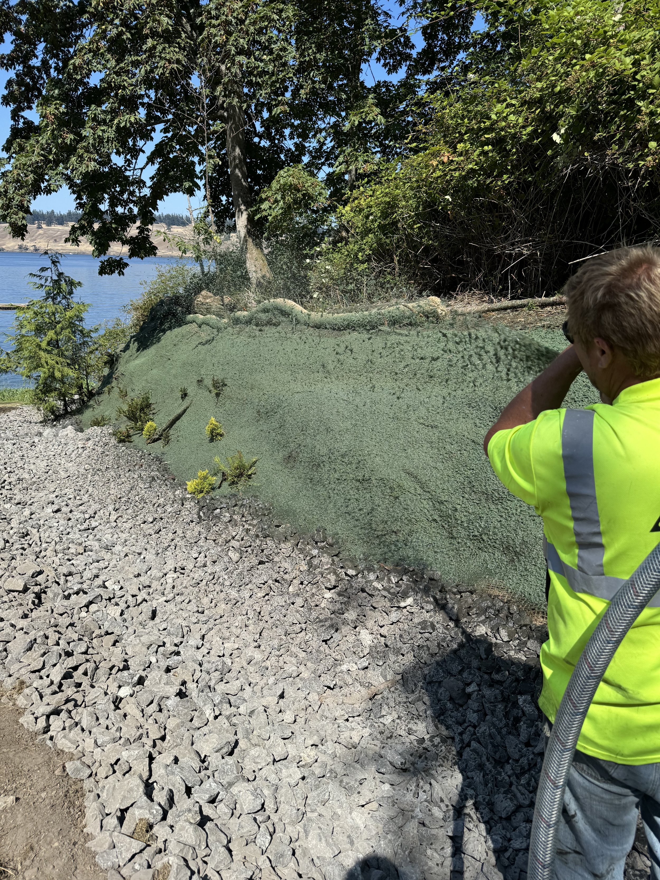 a lawson worker hydroseeding the side of a path
