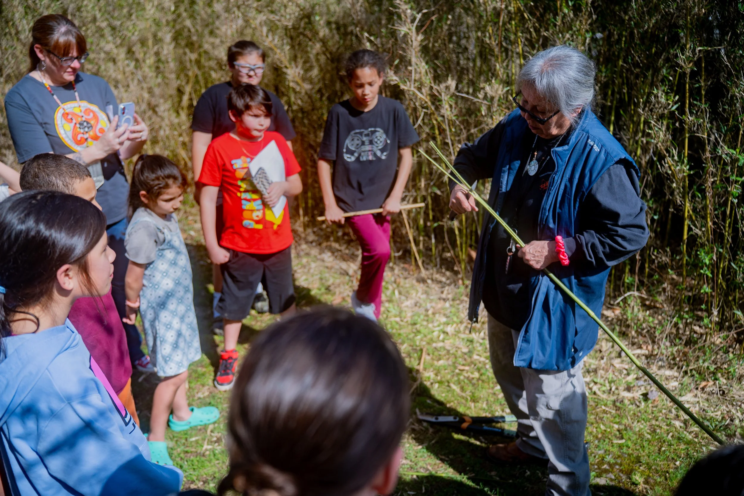 EBCI Elder Mary Thompson showing a group of kids how to spilt rivercane