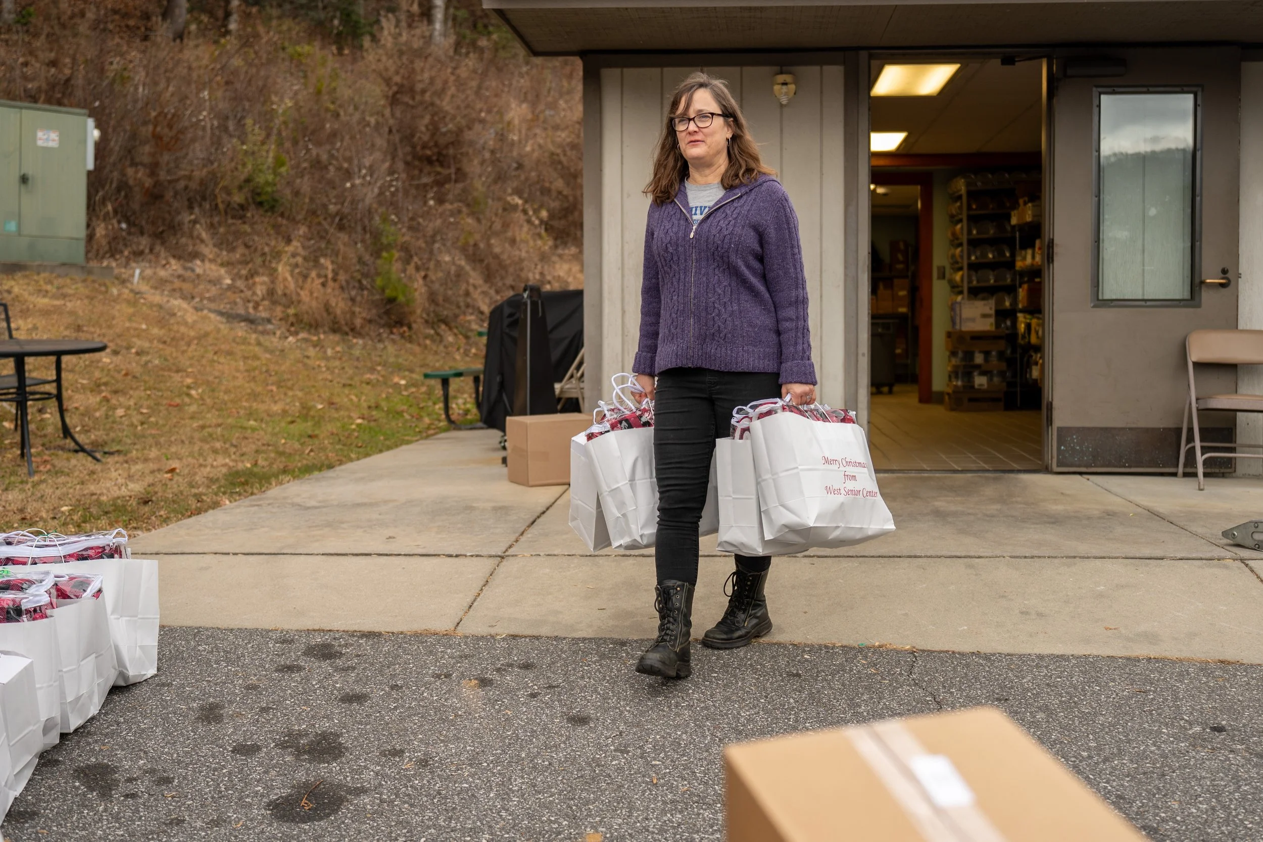 person carrying gift bags to cars