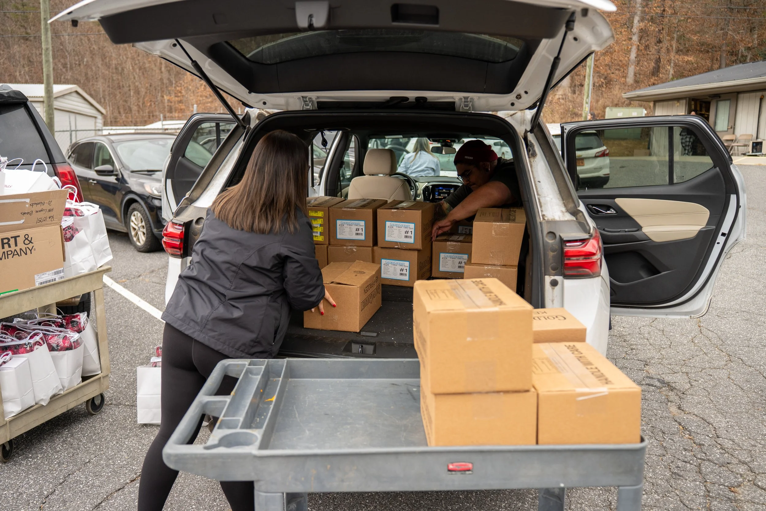 two people loading food boxes into a car