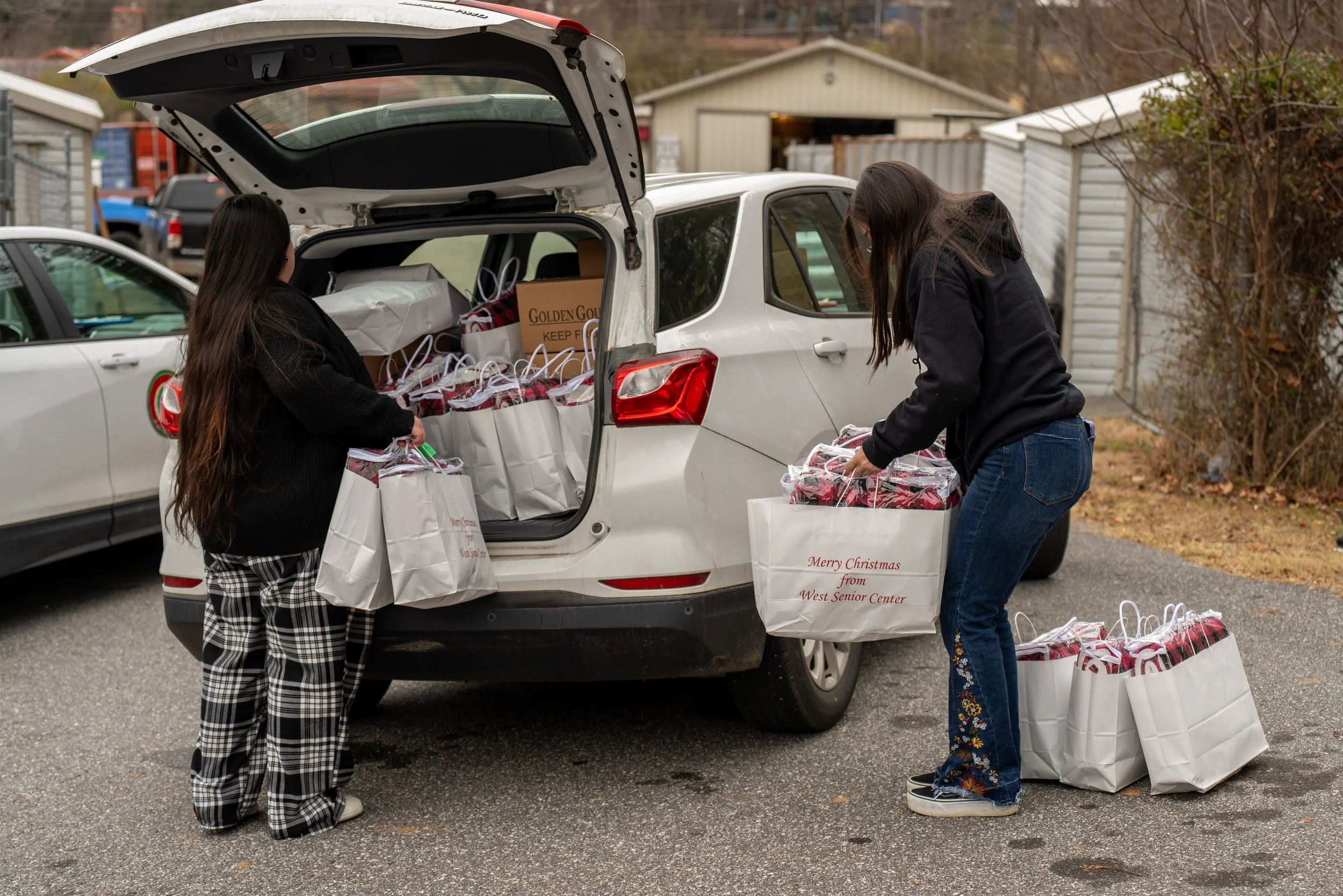 two people loading food boxes into a car