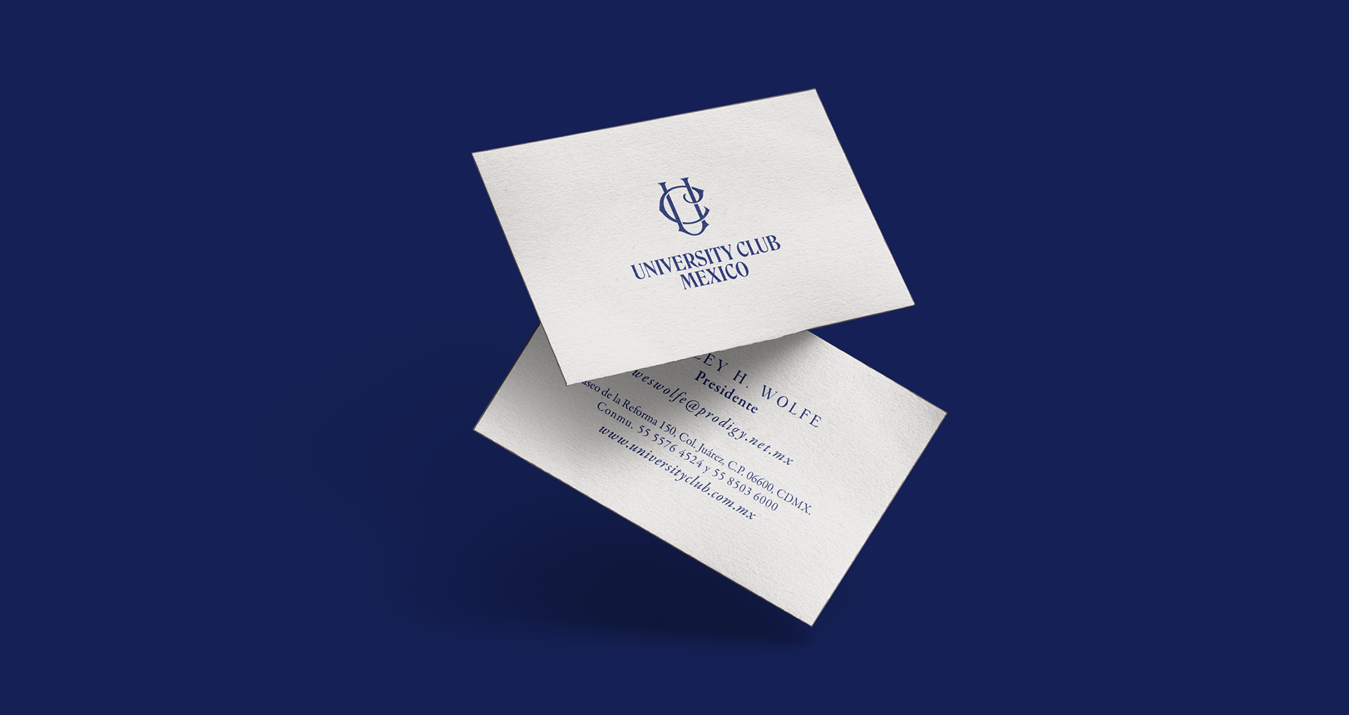 Business cards for University Club Mexico, featuring a blue logo and contact information on a white background, set against a dark blue surface.