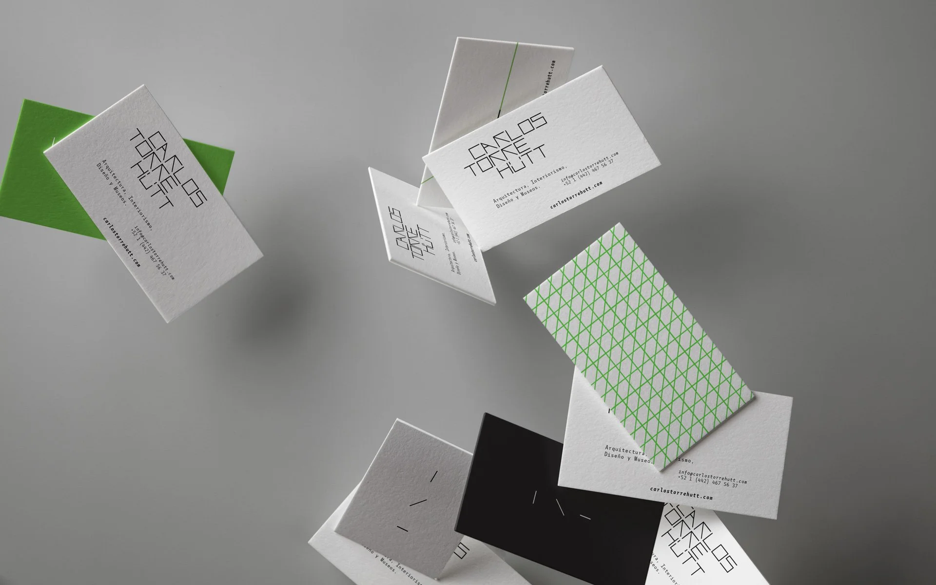 Tarjetas de visita con diseño moderno y geometrico, en colores blanco, negro y verde, flotando en un fondo gris.