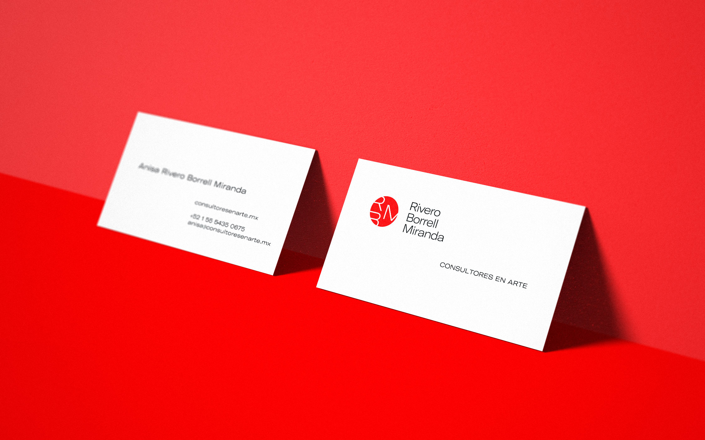 Two white business cards on a red background. One card displays the name Anais Reyes Borrell Miranda, a website, phone number, and email. The other card features a red circular logo and the name Rivero Borrell Miranda, with a tagline in Spanish.