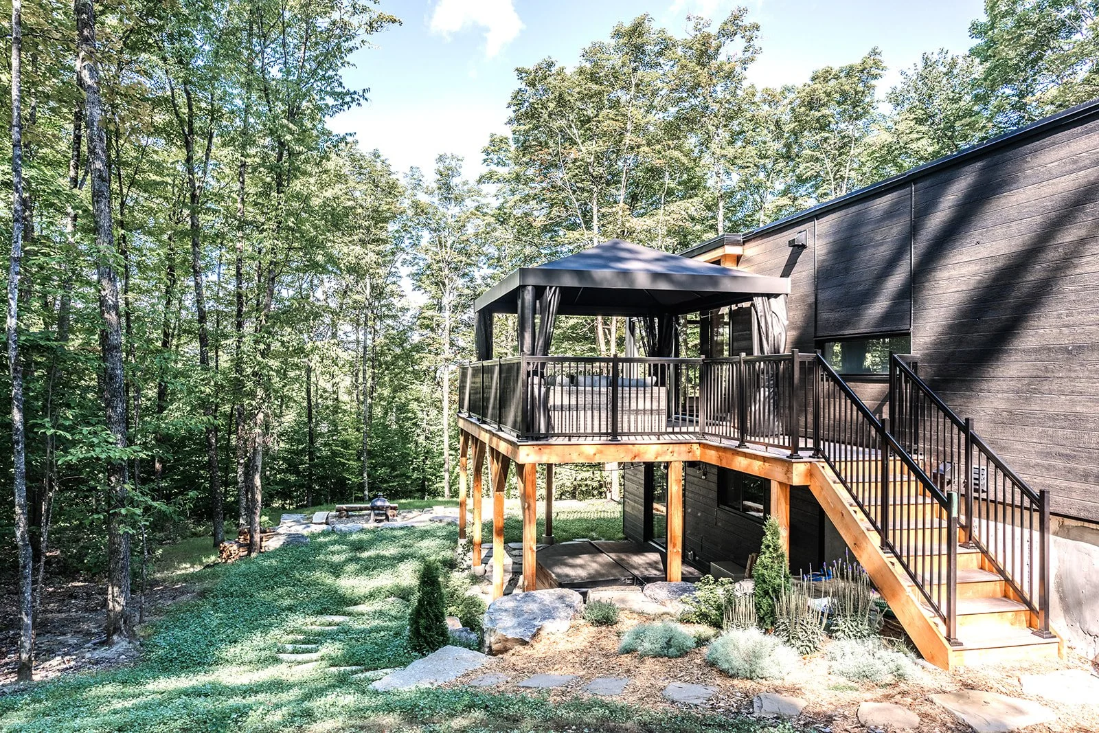 Terrasse arrière équipée d’un pavillon Jardin de Ville haut de gamme, avec moustiquaires pour savourer la forêt sans être dérangé par les insectes.