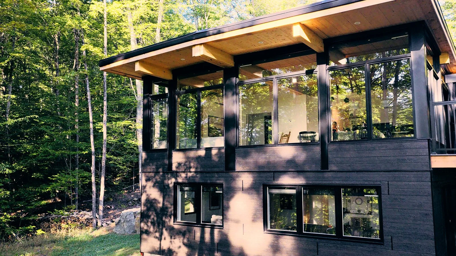 Architecture contemporaine vitrée, baignée de lumière et ouverte sur la nature environnante.
