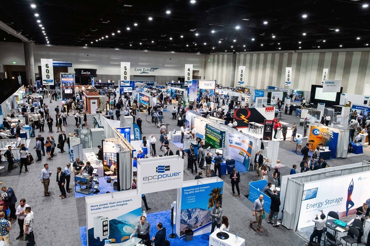 Trade show with numerous booths, banners, and attendees in a large convention hall, showcasing technology and energy storage products.