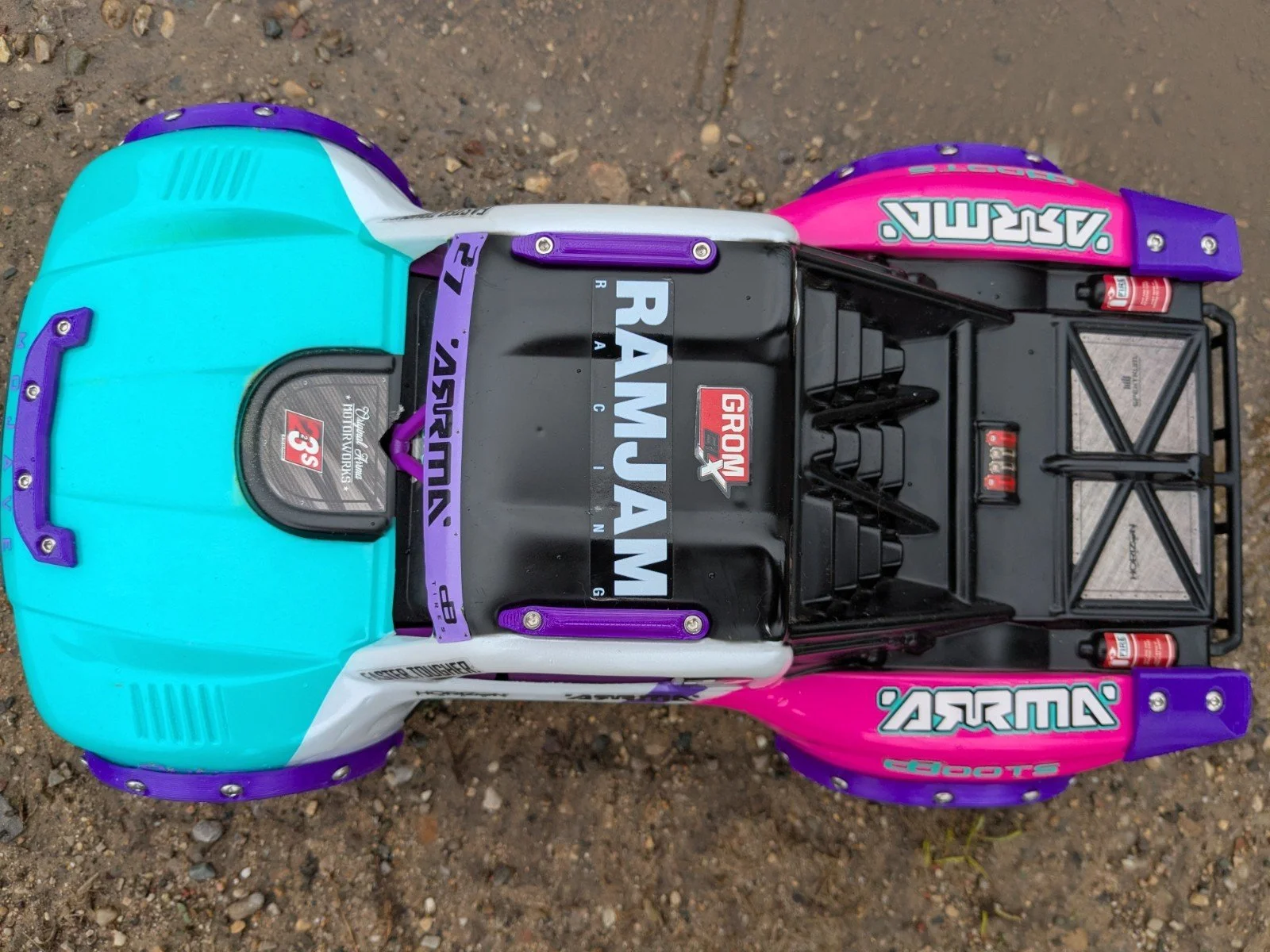 A detailed model of a racing truck with a colorful design, including turquoise, pink, and purple accents, featuring various sponsor logos and decals.