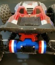 A remote-controlled toy race car with a red and black body, blue wheels, and a blue motor component underneath.