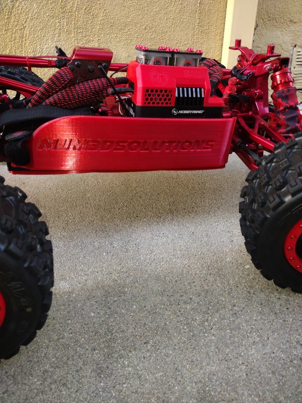 Red off-road remote control car with large tires, red chassis, and various mechanical parts visible.