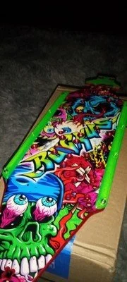A colorful pinball machine with cartoonish skulls and characters, placed on a cardboard box.