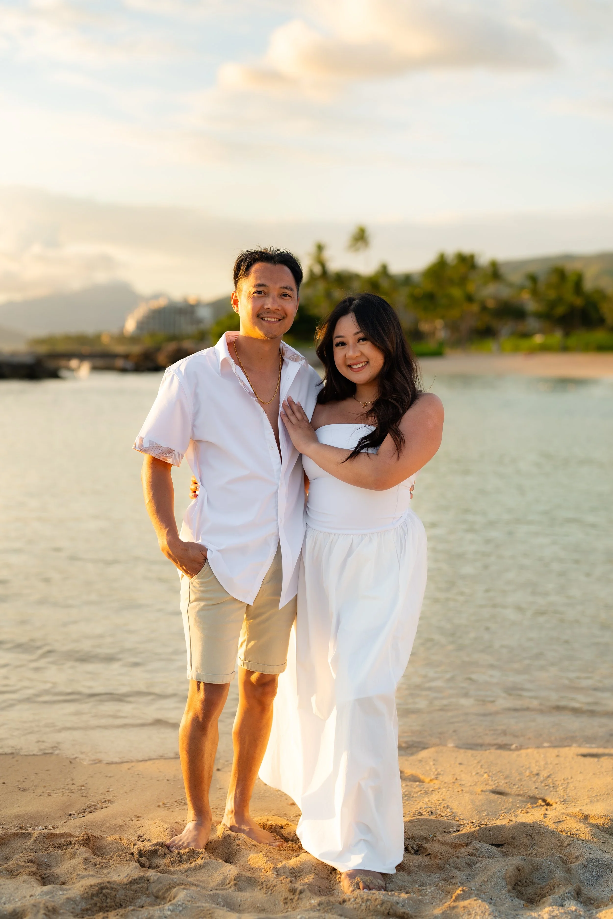 A bride in a white dress holding a bouquet of white flowers, standing outdoors in hawaii taken by aloha media weddings