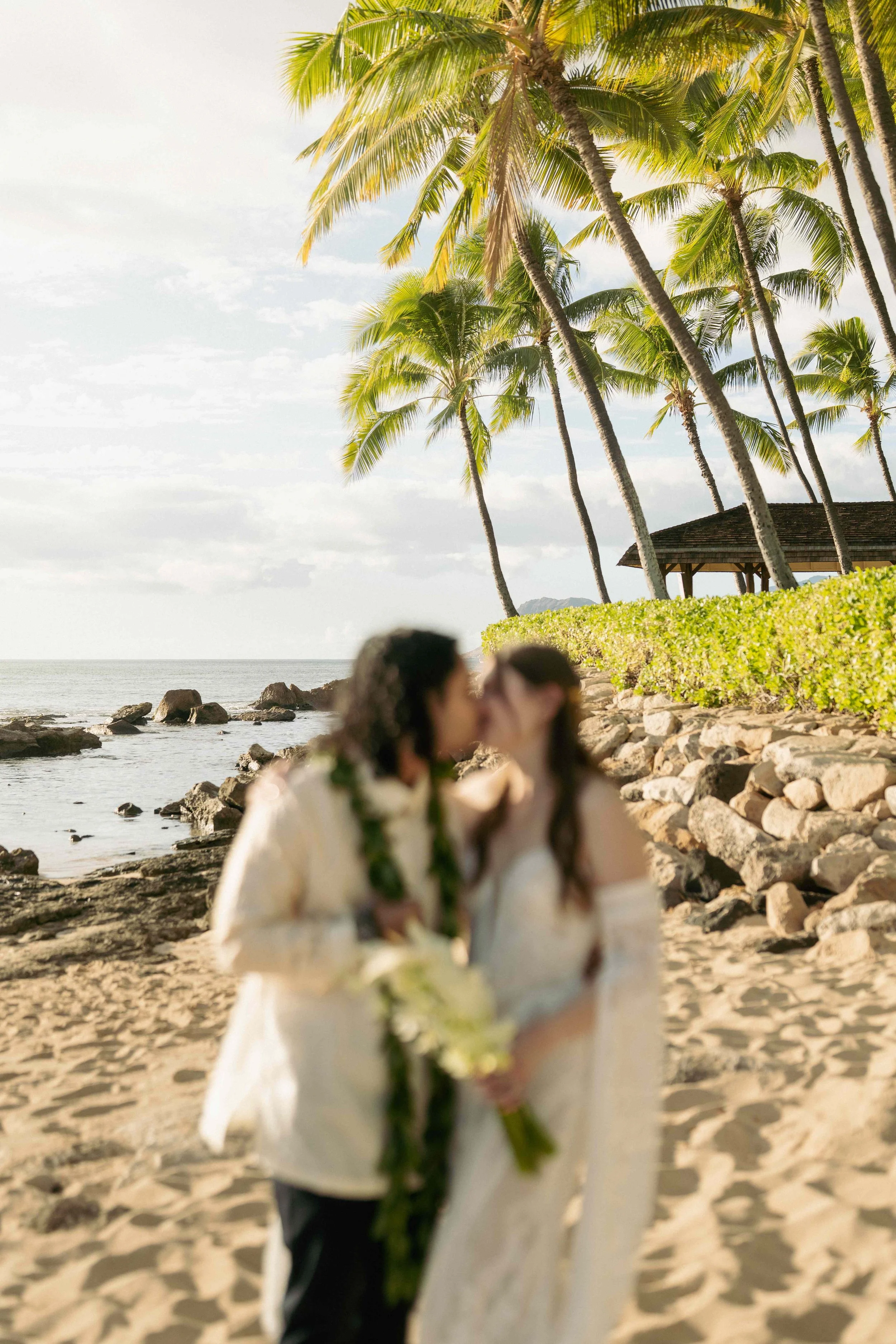 Bride and groom first kiss during outdoor ceremony at Lanikuhonua Ko Olina Oahu Hawaii.