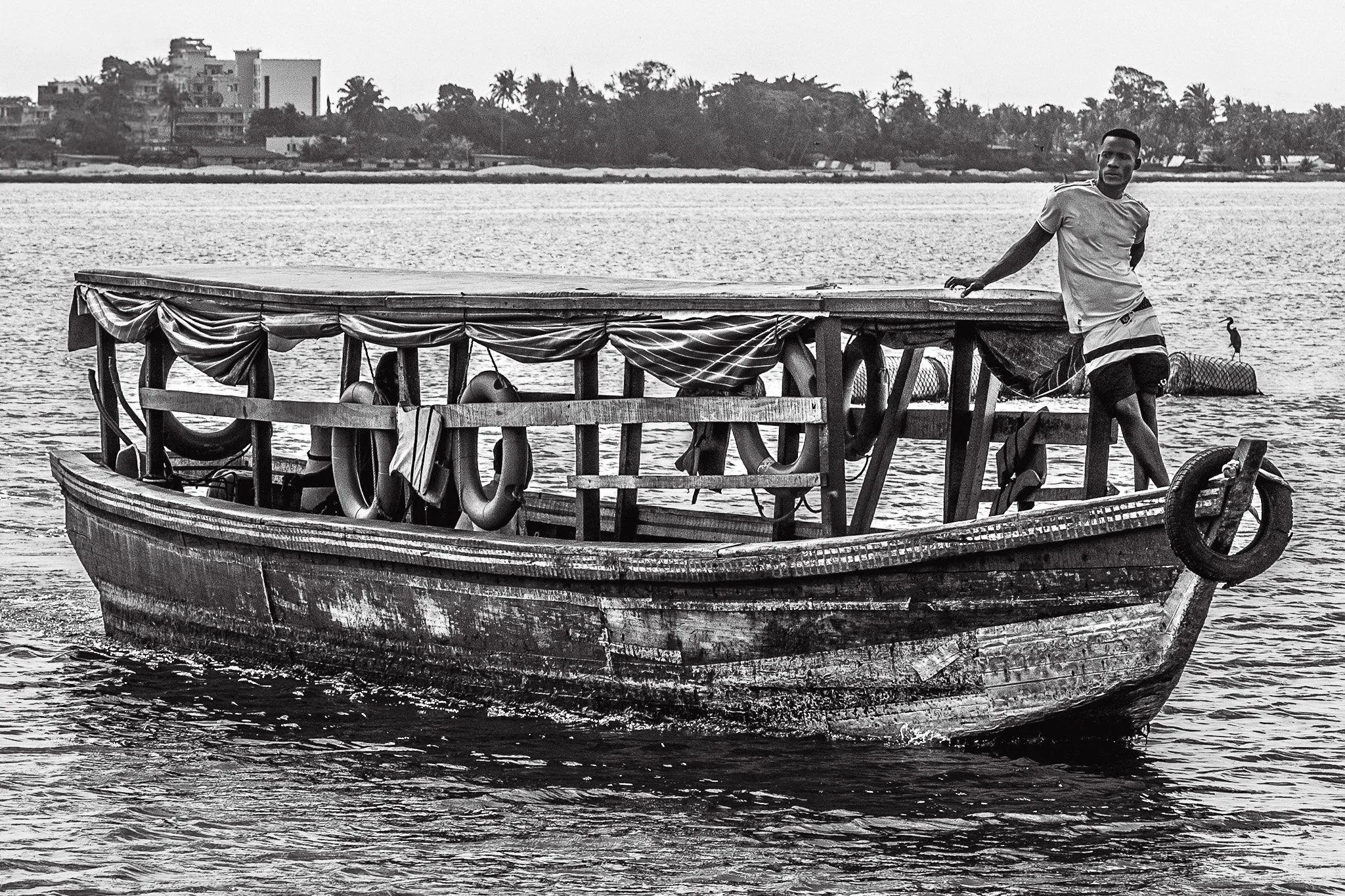 EASY GOING - Could it be the appeal of an old boat slowly cruising down the lagoon or the imperturbable air of the young sailor with his carefree stance that inspired the taking of this photo? Not sure...