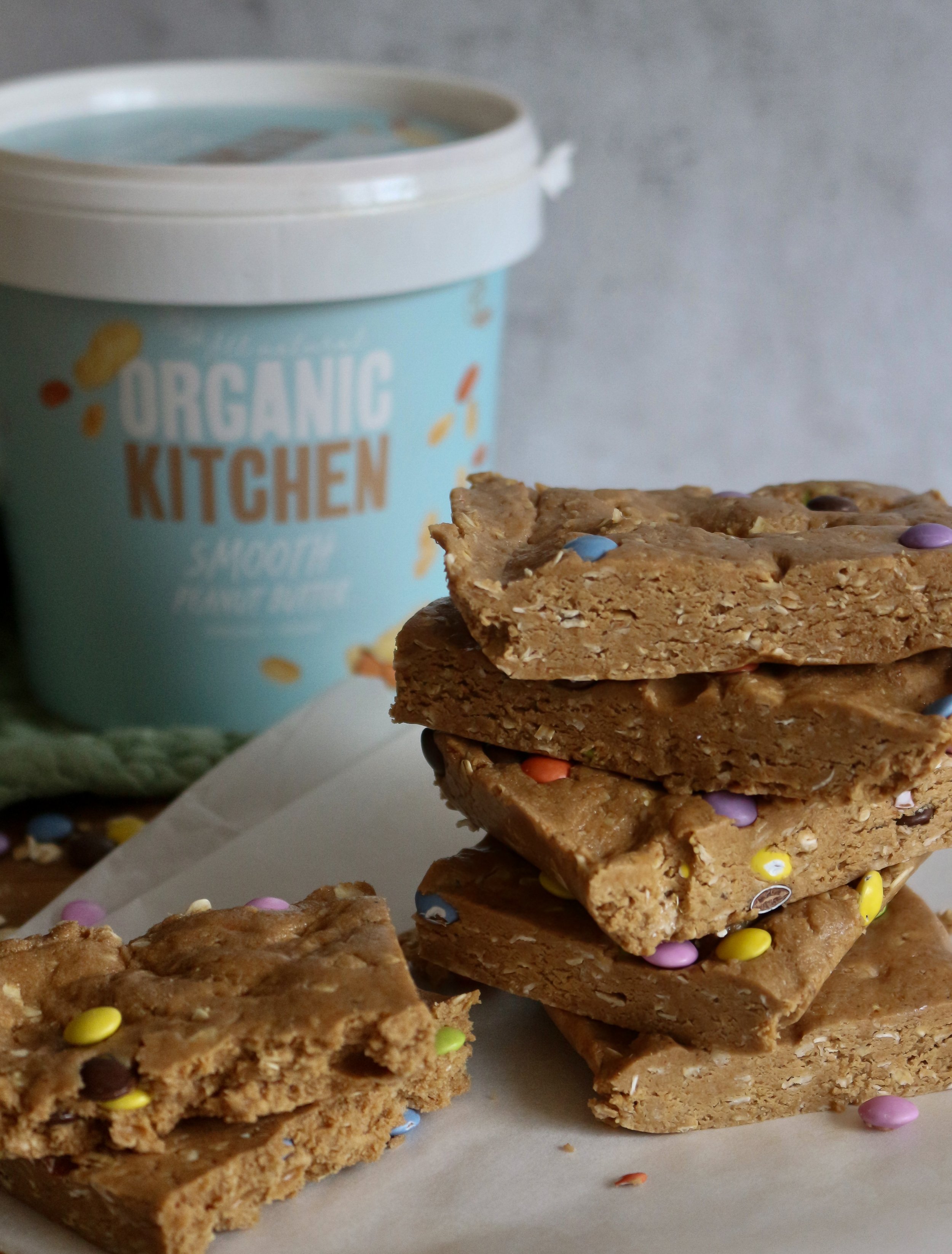 Stack of assorted cookie bars with colorful candy sprinkles in front of an organic kitchen ice cream container.