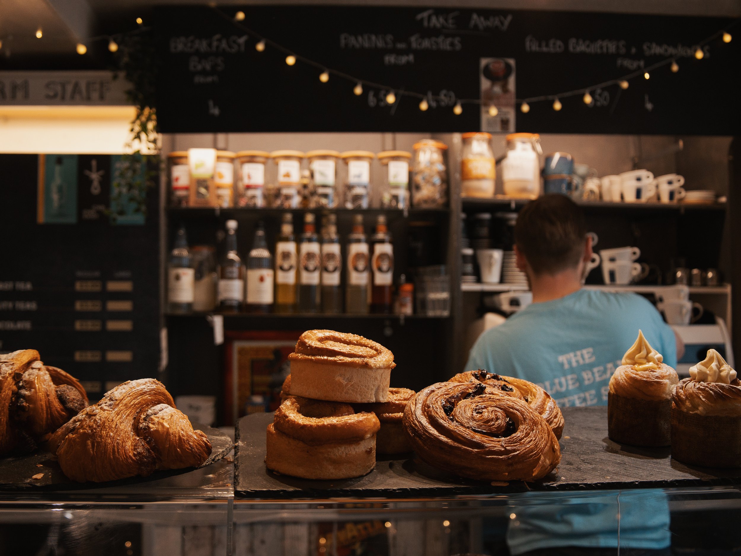 assorted fresh baked pastry items including croissants, cinnamon rolls, and Danish pastries displayed on a counter in a bakery