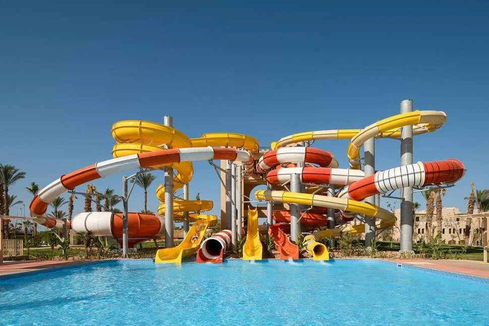 Kleurrijke waterglijbanen bij een waterpark met een zwembad op de voorgrond en palmbomen op de achtergrond. Dit beeld past perfect bij een zonnige gezinsvakantie, all inclusive resorts en kindvriendelijke hotels met waterparken.