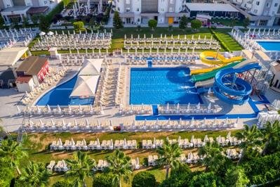 A water park with multiple water slides and pools, surrounded by lounge chairs and lush greenery.