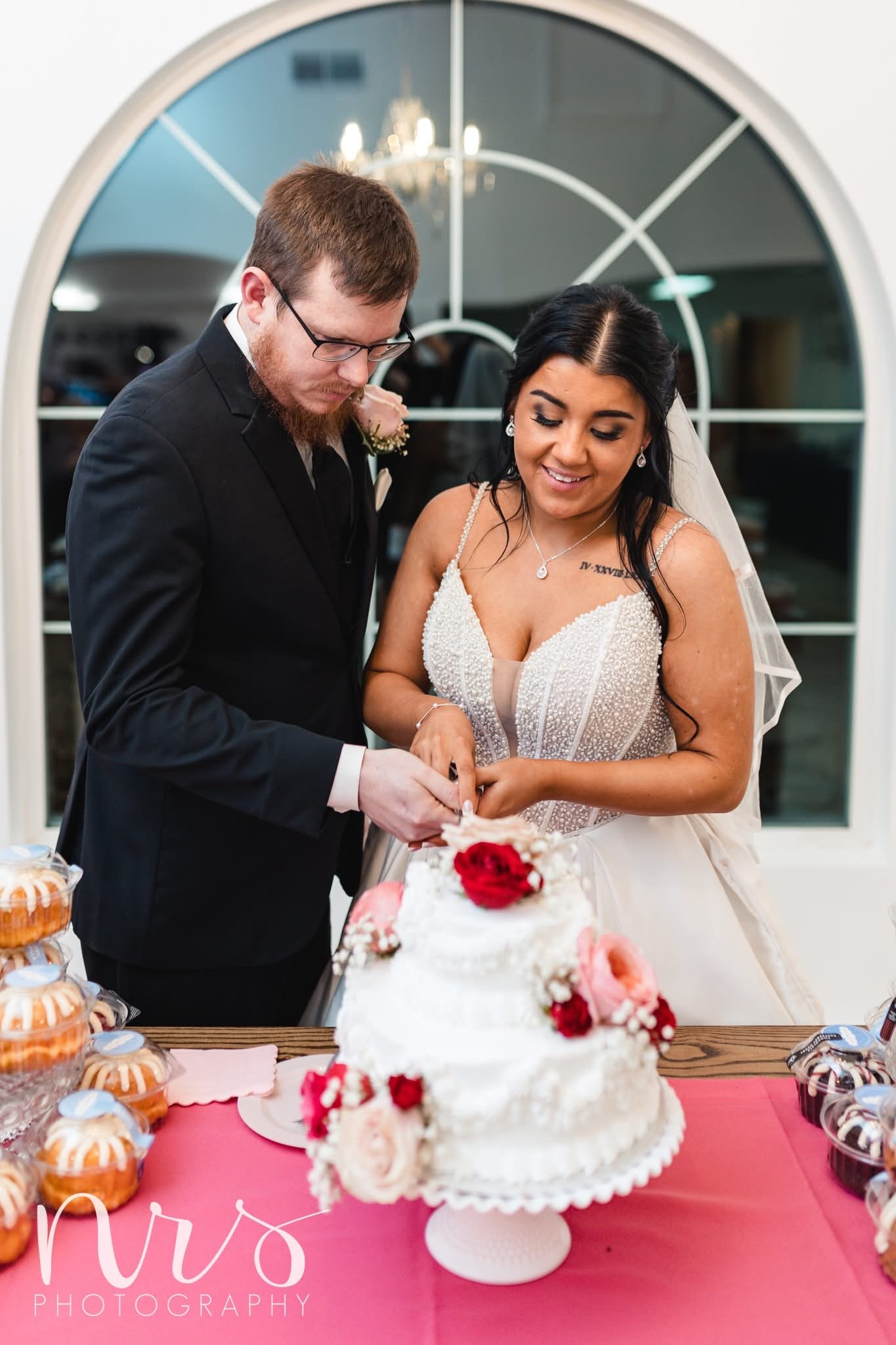 Cake cutting at wedding reception with chandelier and bright backdrop near Westville, IL

