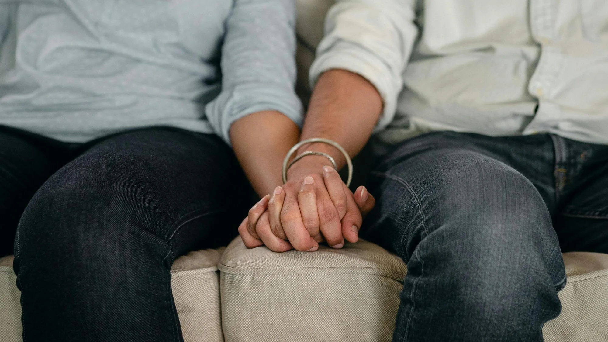 couple sitting on couch holding hands