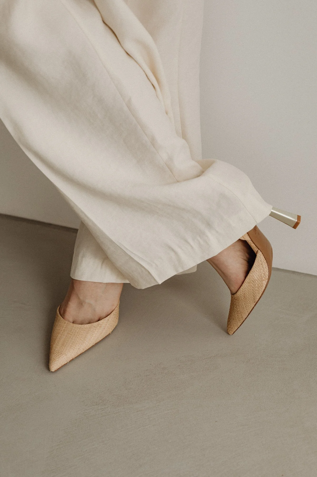 woman in heels standing with legs crossed and ivory pants