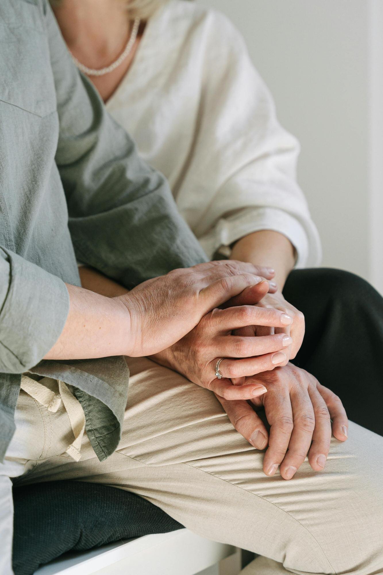 couple holding hands - man in khaki pants and olive colored shirt woman in black pants and white blouse