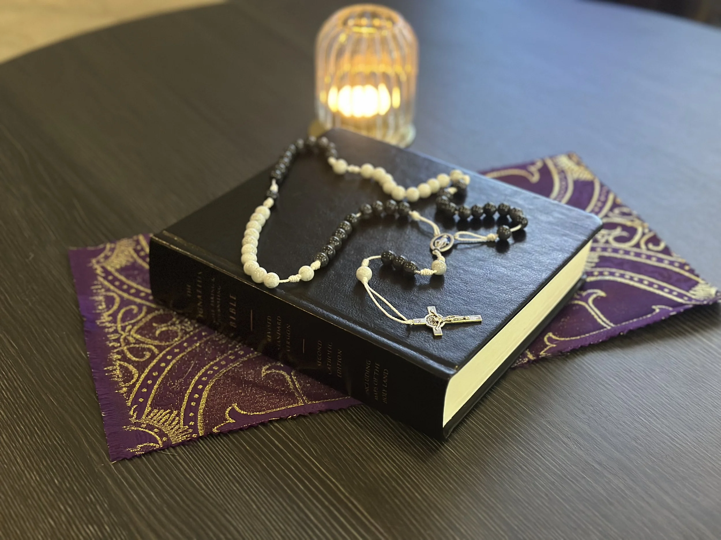 The Integrated Path Rosary with alternating black and white glass beads on a crisp white cord.