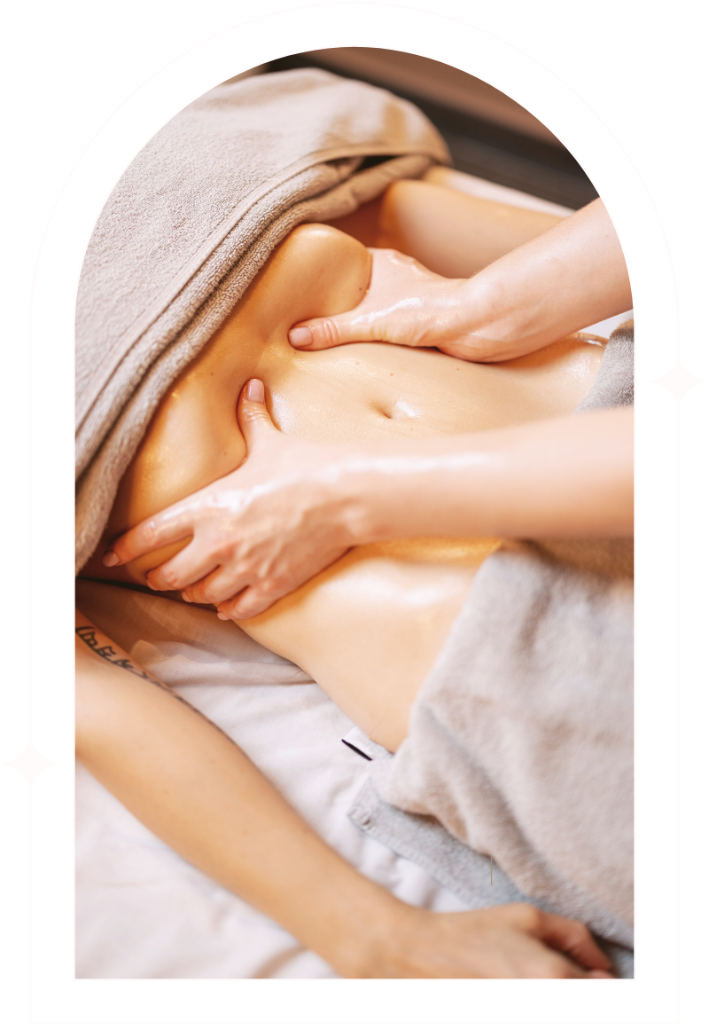 Person receiving a massage on their abdomen during a massage session, with a towel covering part of their body.