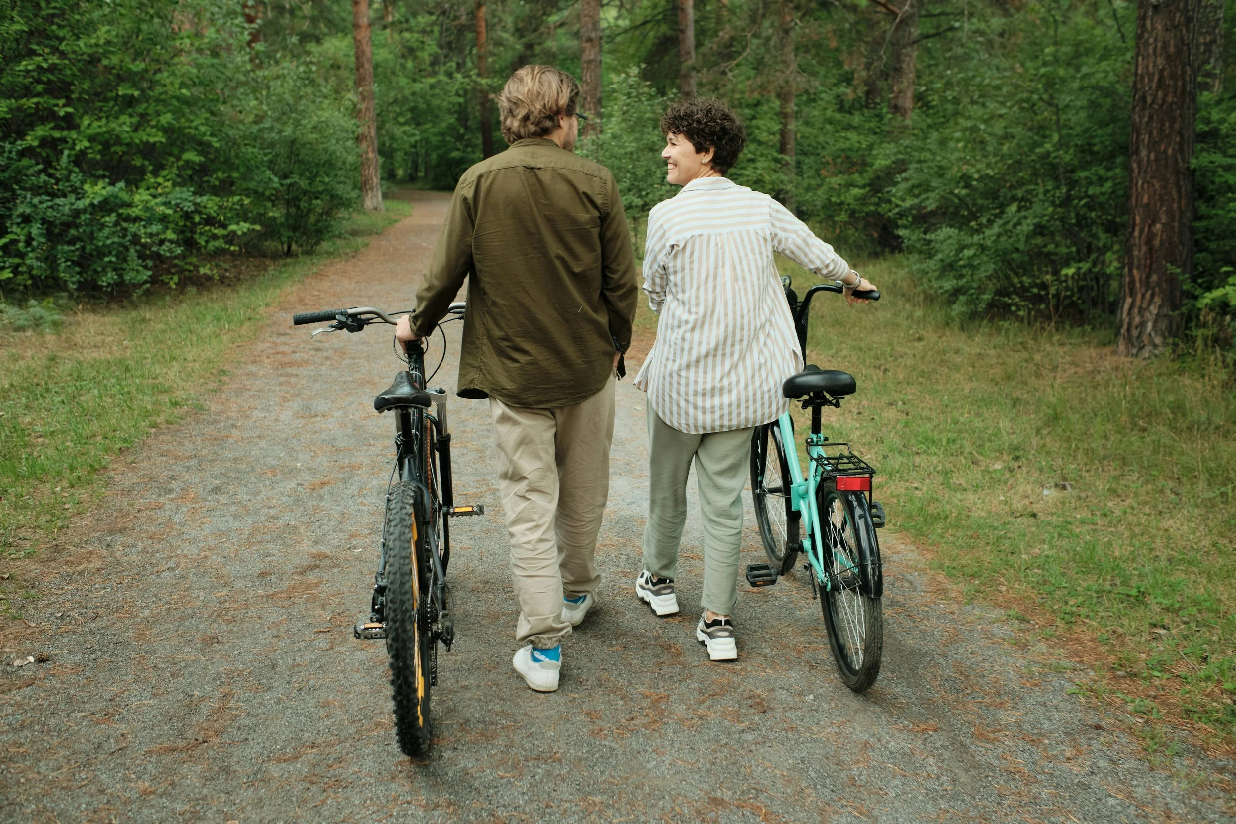 A couple considers their future as they walk their bikes down a path in Houston's Loop neighborhood. They're glad they pursued EFT based therapy at Heights Couples Therapy.