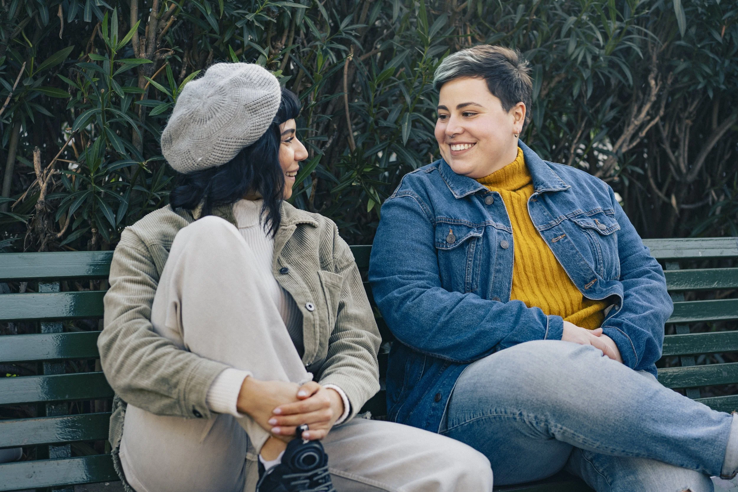Two partners talking on a park bench, illustrating open communication about relationship boundaries and ENM agreements.