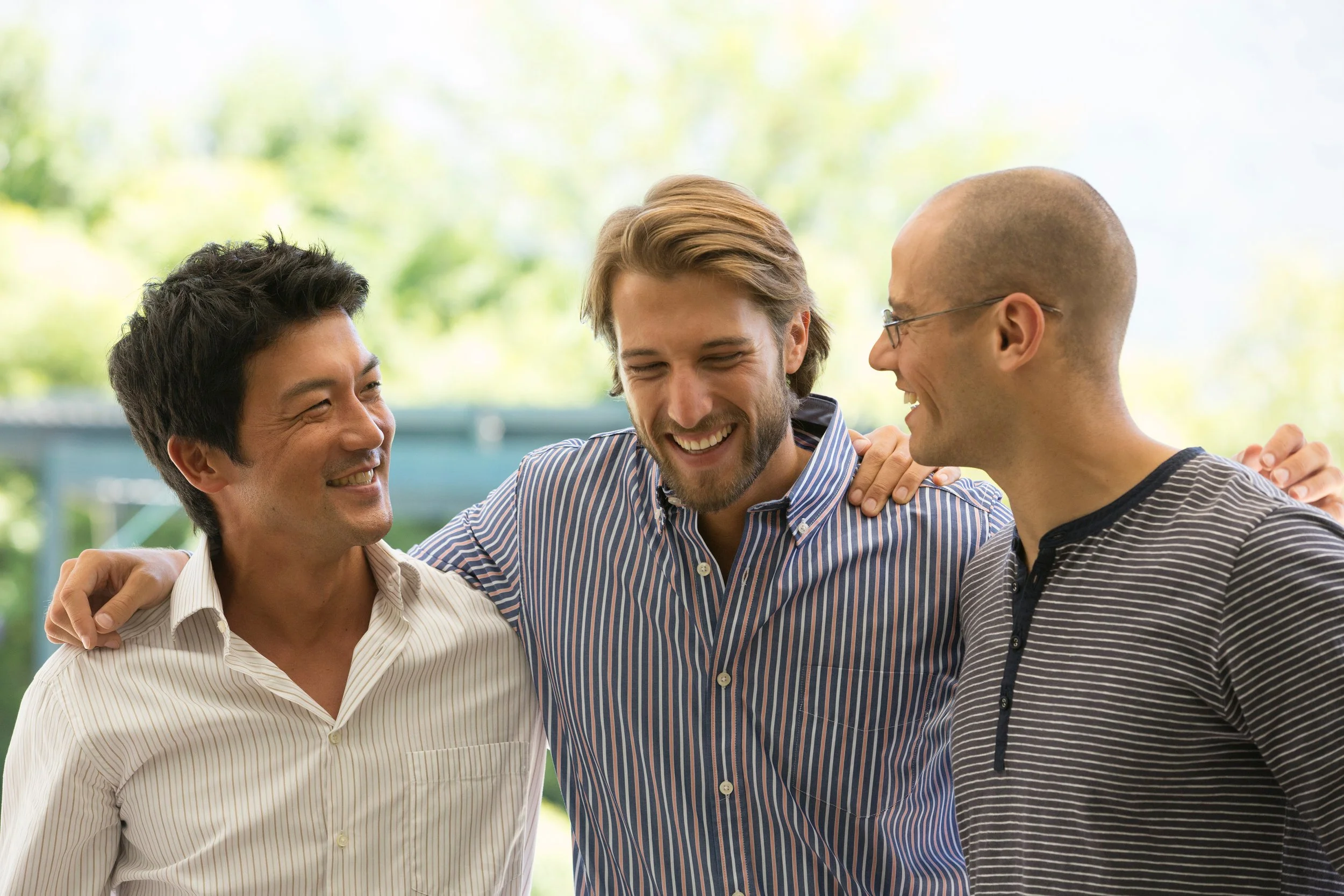 Three partners smiling together, representing ethical non-monogamy and the importance of clear ENM agreements and relationship boundaries.