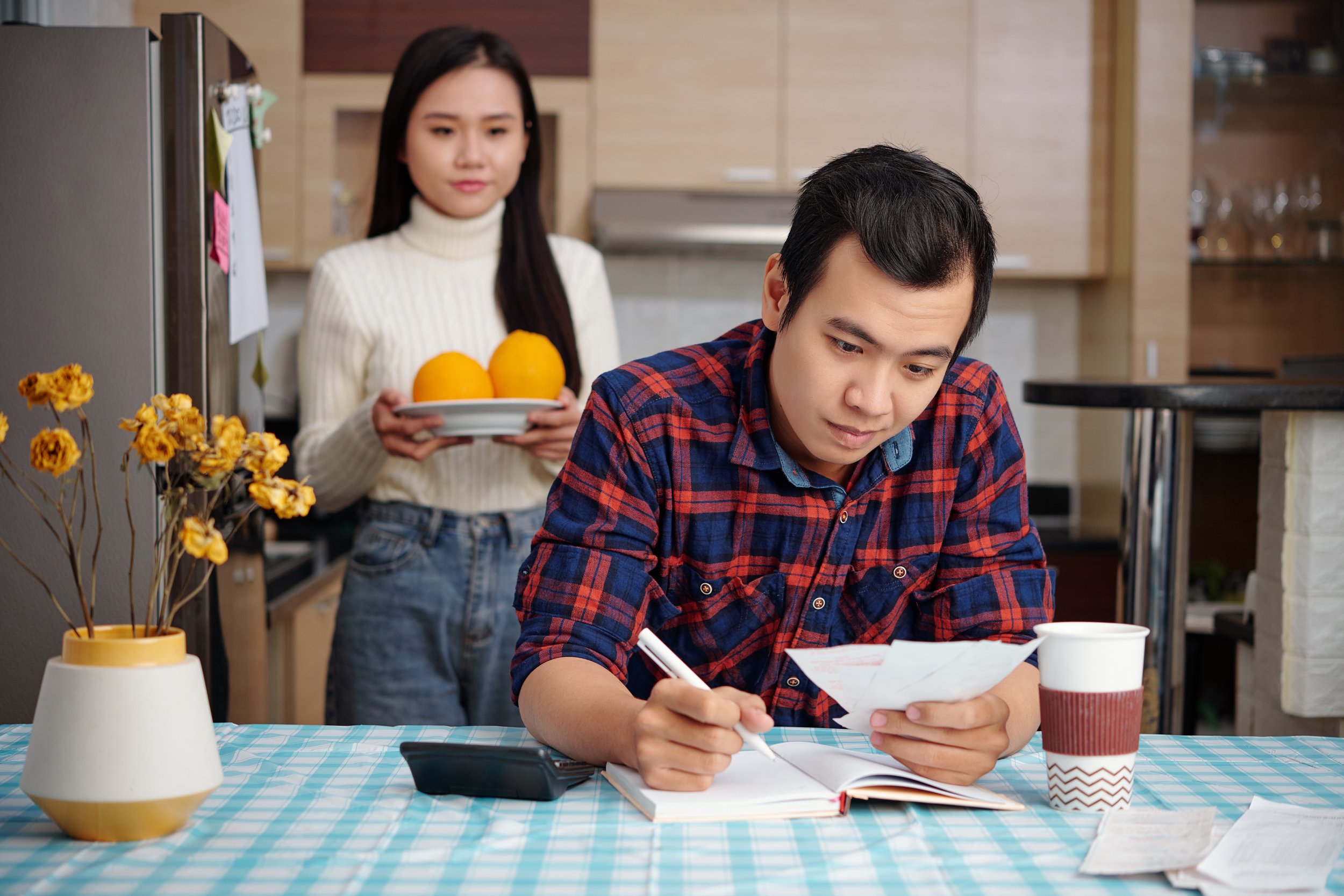 Woman brings food to her partner while he manages household finances, showing how individual relationship therapy and avoidant partner therapy can support reconnection through everyday care.