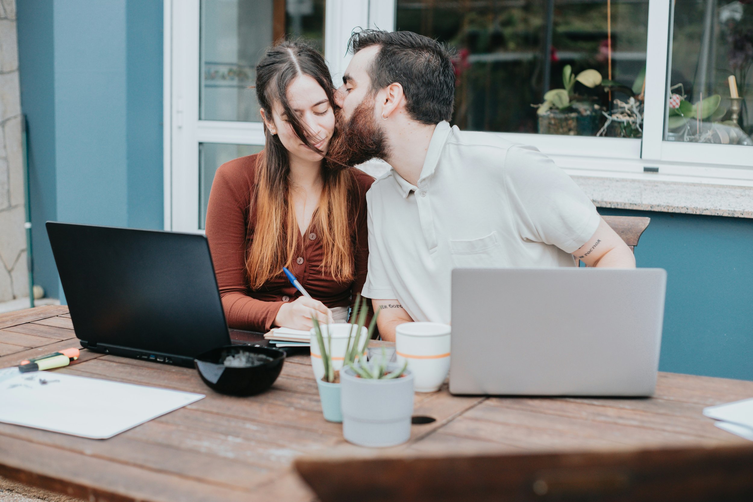 Dual-career couple sharing a moment of affection while managing work together at home.