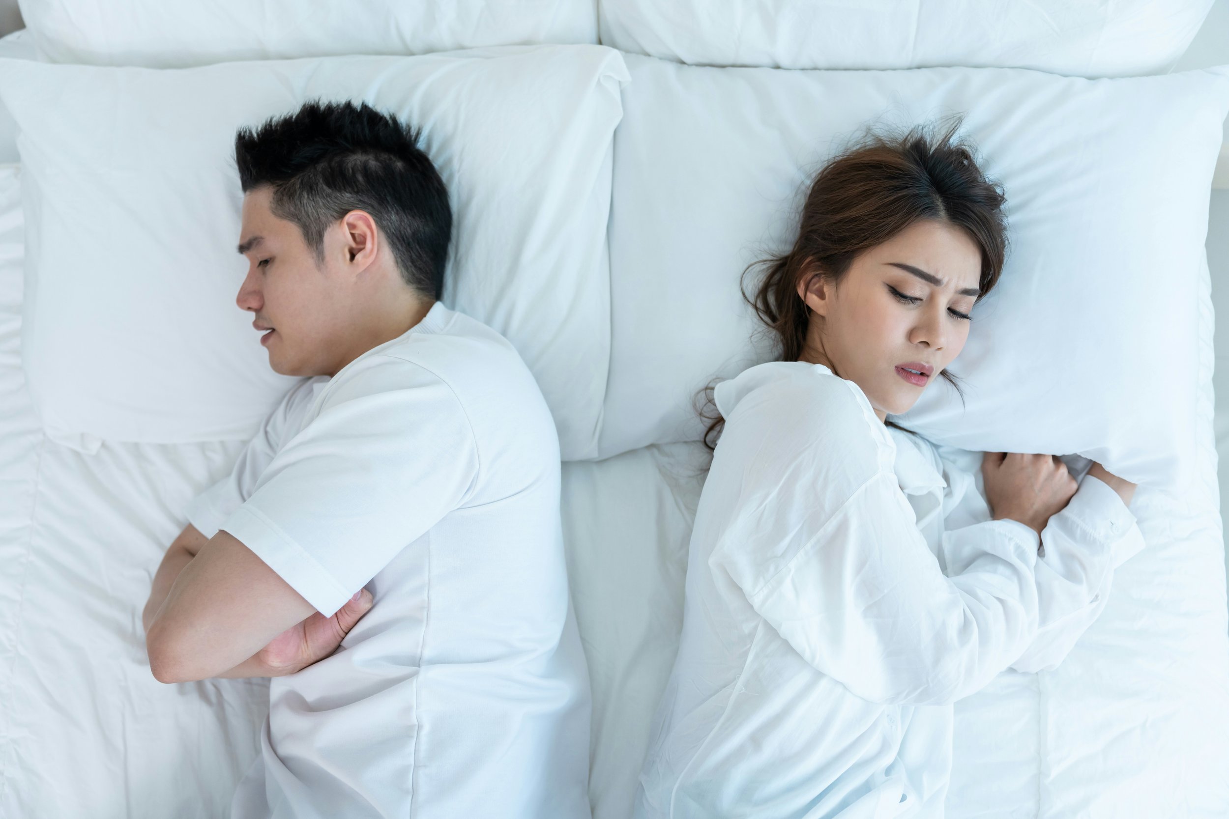 A woman wonders about her emotionally unavailable partner while they both lie in bed. She is concerned about his anxiety or addiciton issues, but knows he won't go to Houston couples therapy.