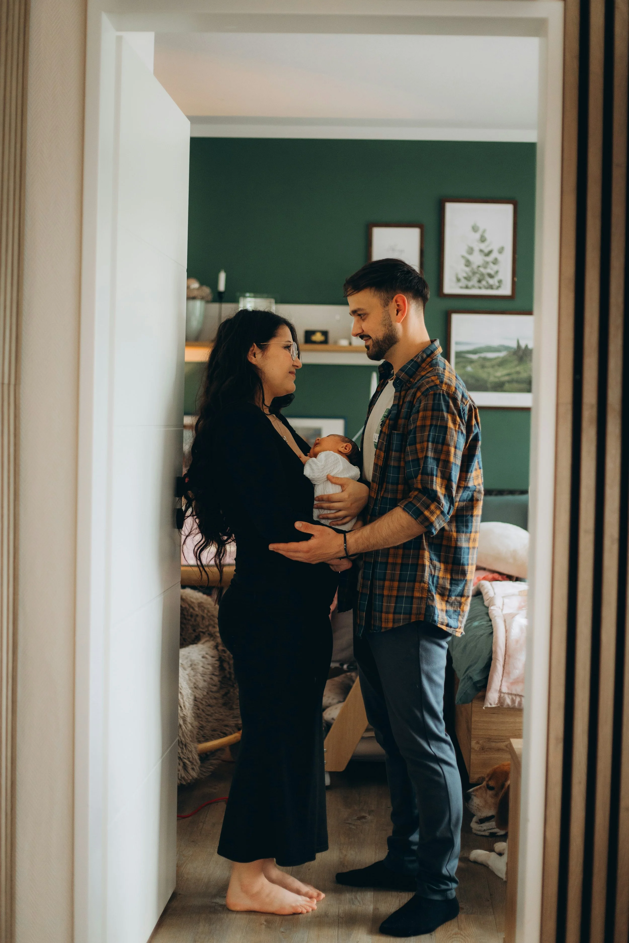New parents standing together while holding their newborn, representing connection and teamwork after having a baby.