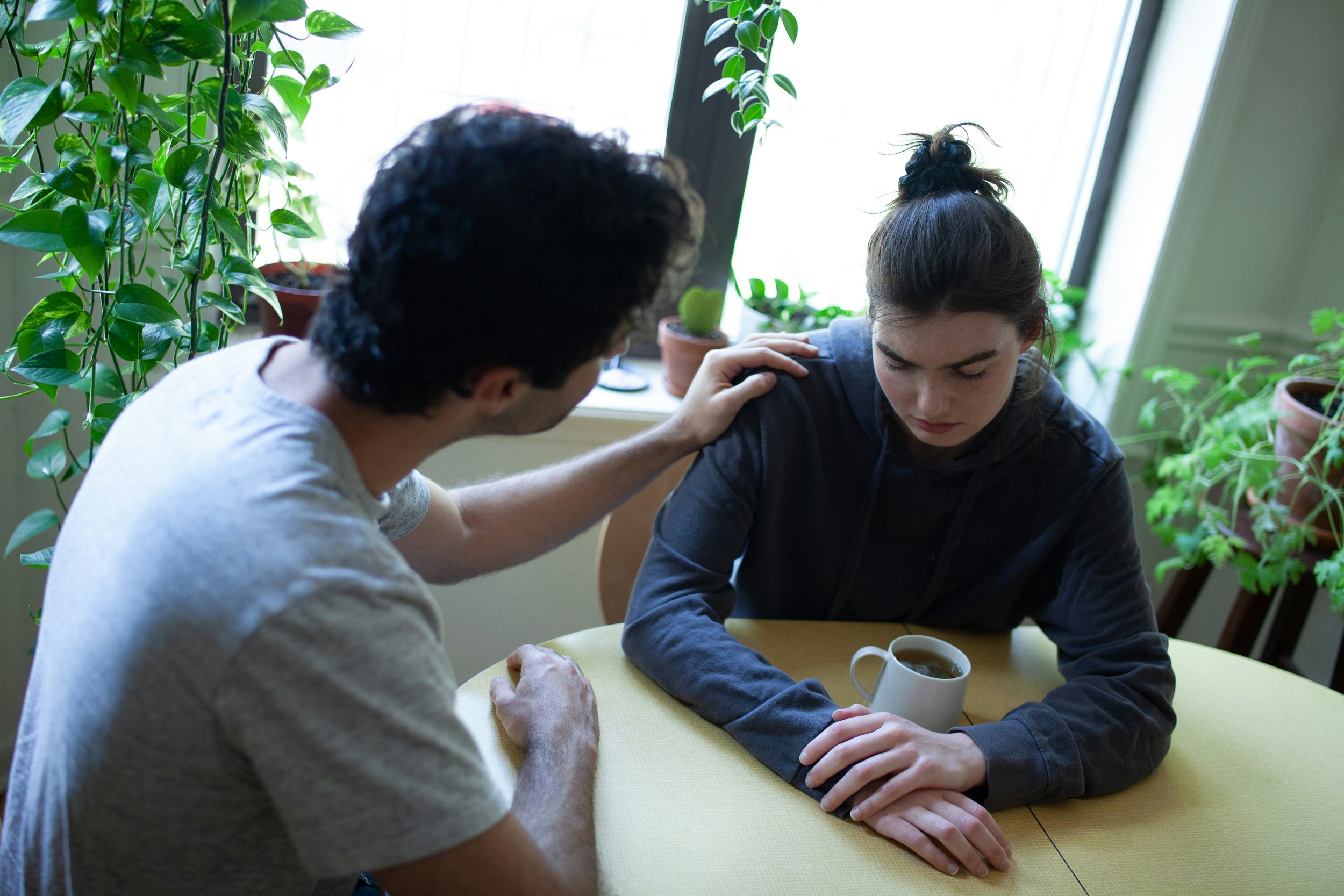 One partner reaching out to comfort the other during a difficult conversation, illustrating the uncertainty many couples feel when they are unsure about divorce.
