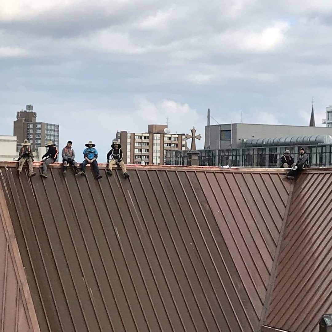 Workers sitting on metal roof in Victoria, BC