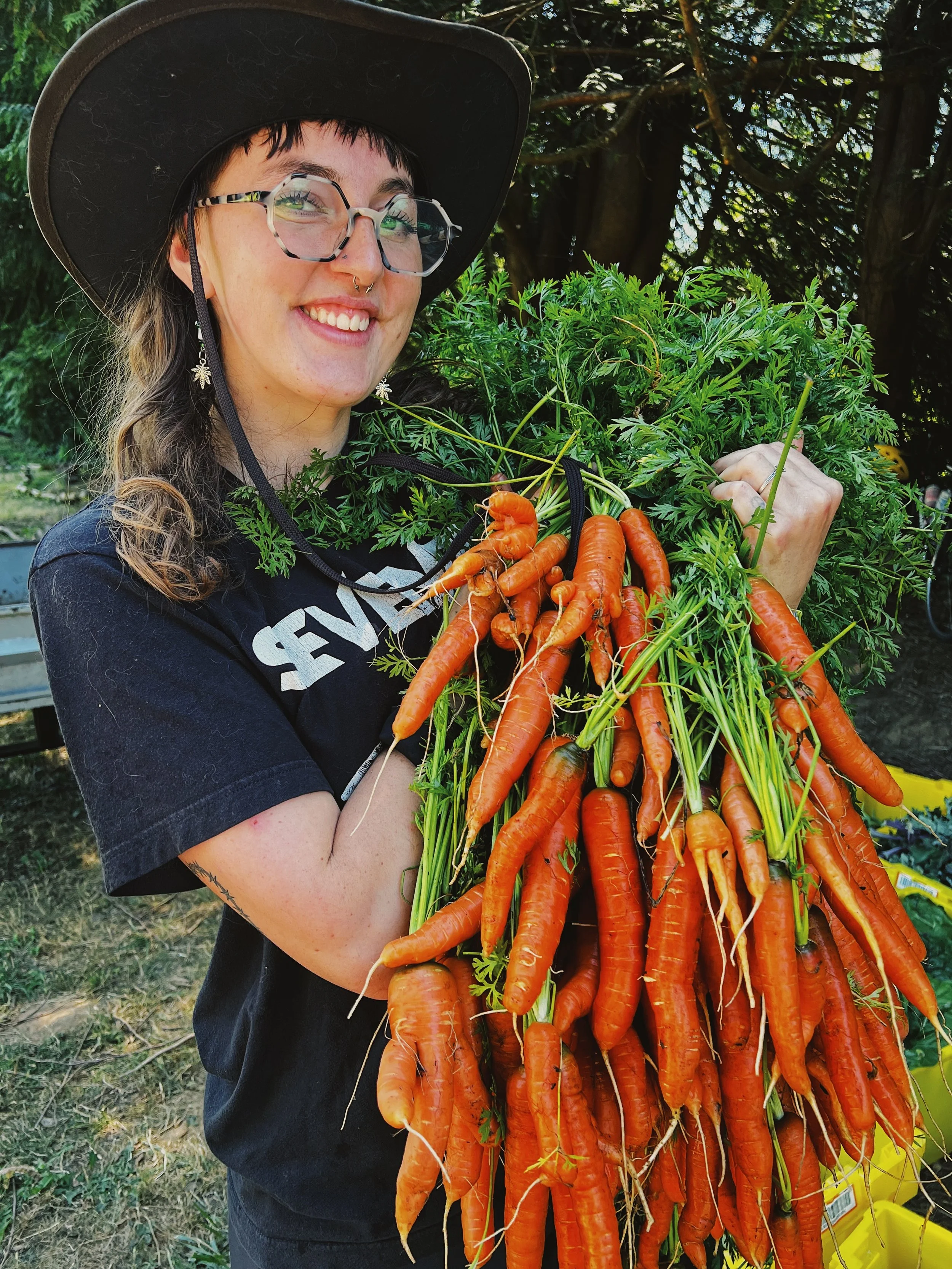 Smiling person holding up carrots